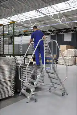 Dobbel plattformtrapp i aluminium i bruk med rekkverk og hjul